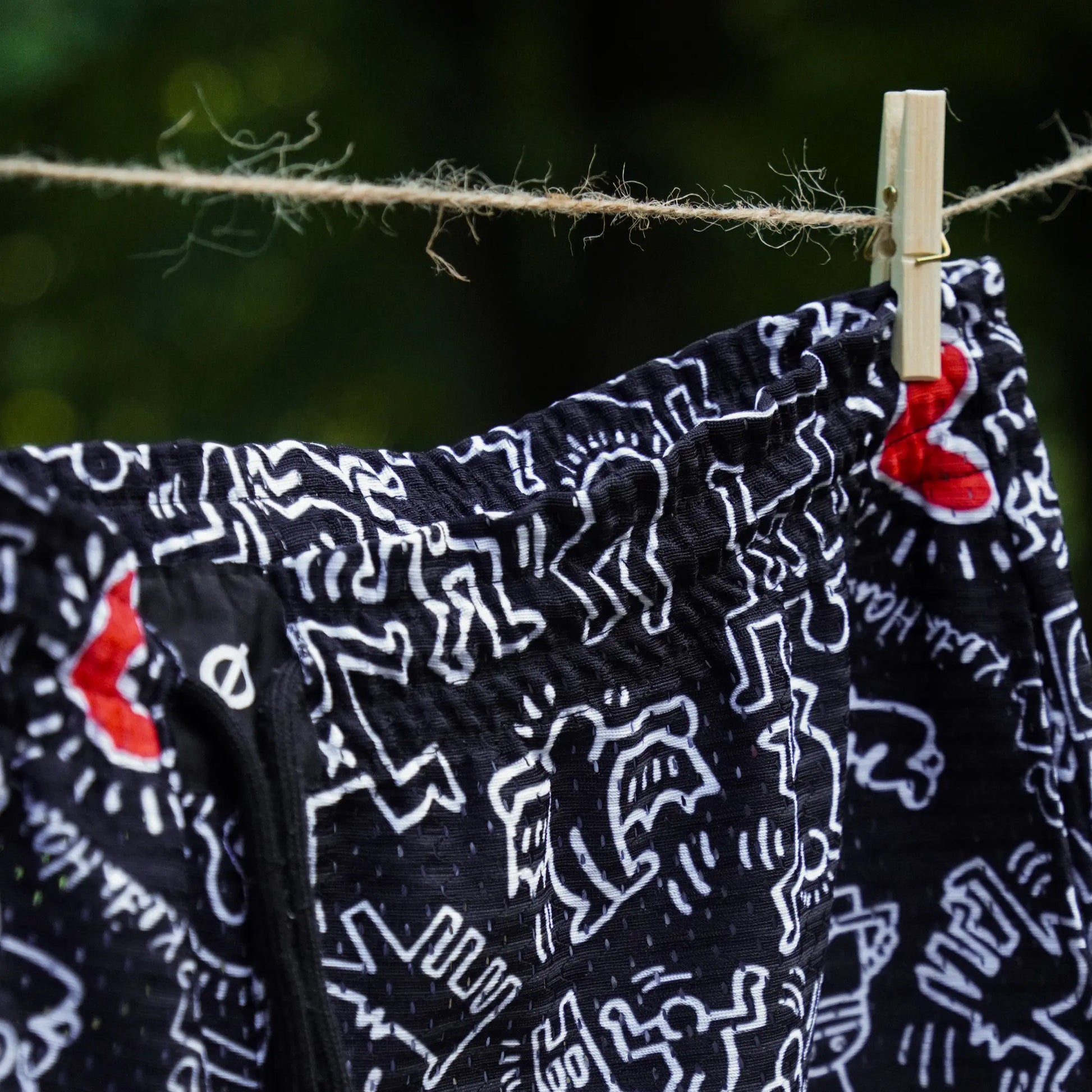Black fabric with white patterns and red accents hanging on a clothesline.